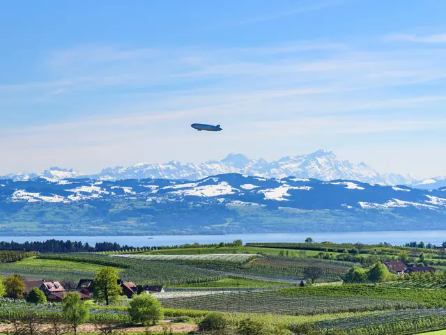 Frühling am Bodensee, rund um den See bei Lindau blühen die Obstbäume, auf den Bergen liegt noch Schnee.