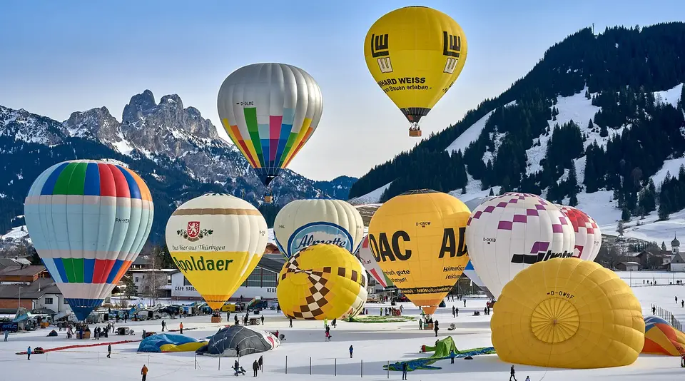 Bunte Heißluftballons beim Ballonfestival im verschneiten Tannheimer Tal in Tirol.