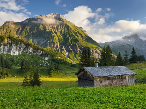 Gemütliche Holzhütte vor der imposanten Juppenspitze im Lechquellengebirge, Vorarlberg, Österreich – alpine Idylle inmitten der Natur.
