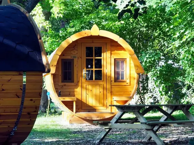 Rundes Holz-Weinfass als Ferienunterkunft im Wald zwischen Bäumen