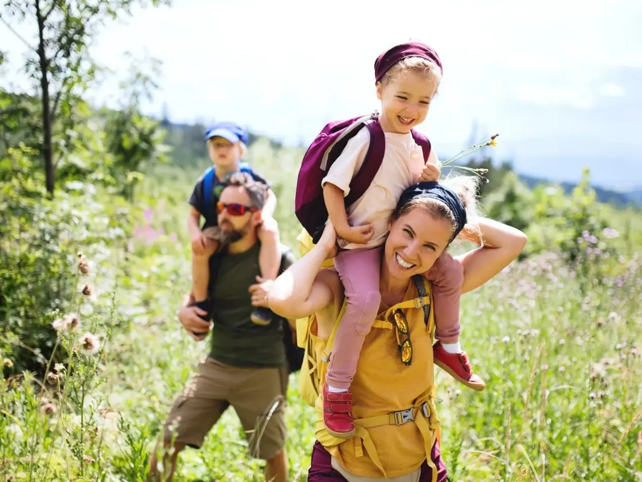 Vorderansicht einer Familie mit kleinen Kindern beim Wandern im Freien in der sommerlichen Natur.