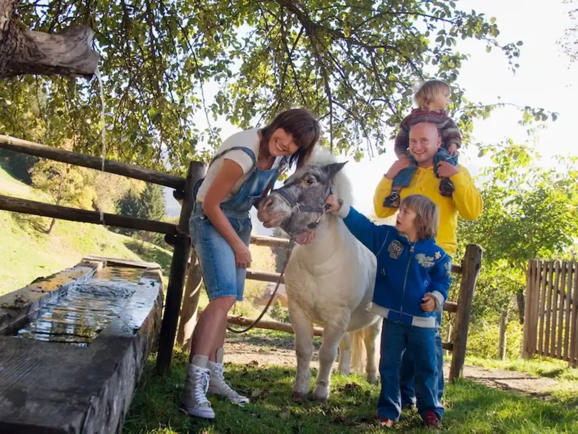 Familie mit Kindern erlebt Urlaub auf dem Land und füttert gemeinsam Tiere auf einem ländlichen Bauernhof.