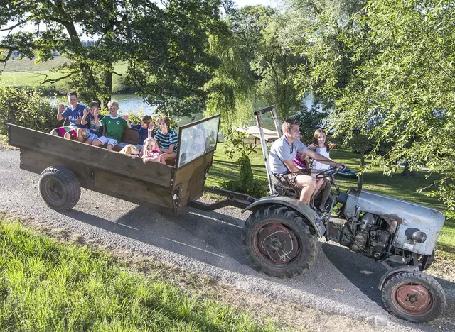 im Familienurlaub auf dem Bauernhof eine Fahrt mit dem Traktor machen