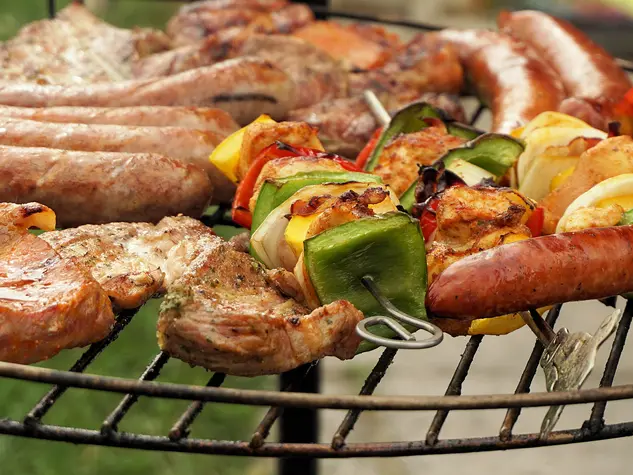 Urlaub auf dem Land: regionale Wurst, Fleisch und Gemüse auf dem Grill zubereiten