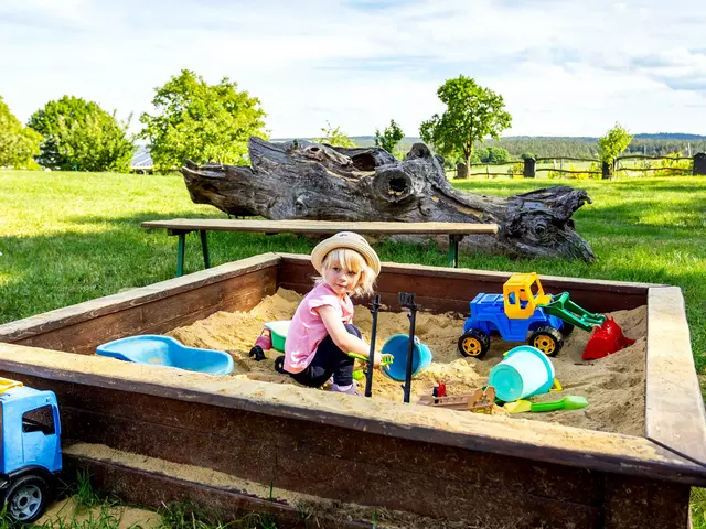 im Urlaub auf dem Kinderhof spielen Kinder im Sandkasten