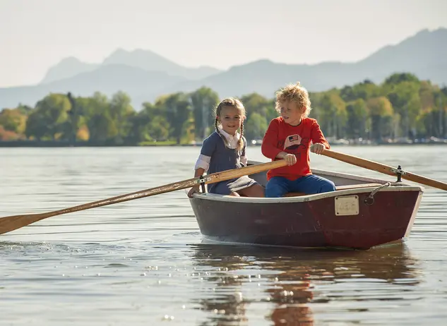 im Familienurlaub auf dem Bauernhof am Chiemsee entdecken Kinder im Ruderboot den See