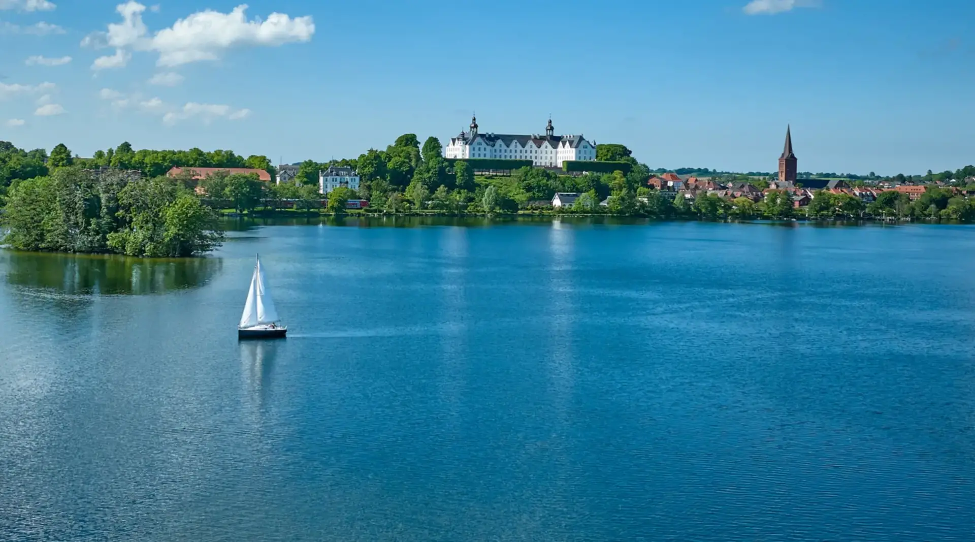 Bootsfahrt auf dem Plönersee - Ausflugsziel beim Bauernhof-Urlaub - © Malopo, AdobeStock Segelbootsfahrt auf dem Plönersee im Hintergrund das Schloss Plön - Ausflugsziel beim Bauernhof-Urlaub