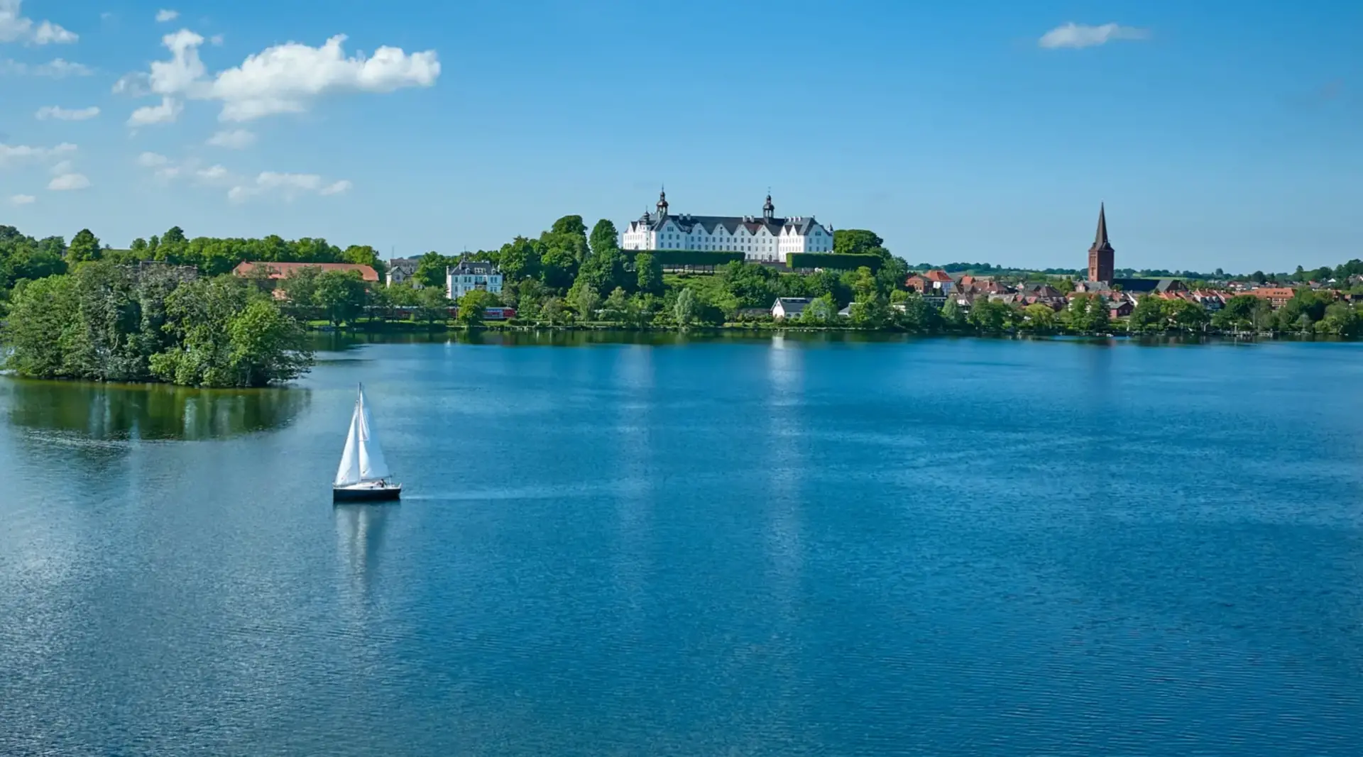 Bootsfahrt auf dem Plönersee - Ausflugsziel beim Bauernhof-Urlaub - © Malopo, AdobeStock Segelbootsfahrt auf dem Plönersee im Hintergrund das Schloss Plön - Ausflugsziel beim Bauernhof-Urlaub