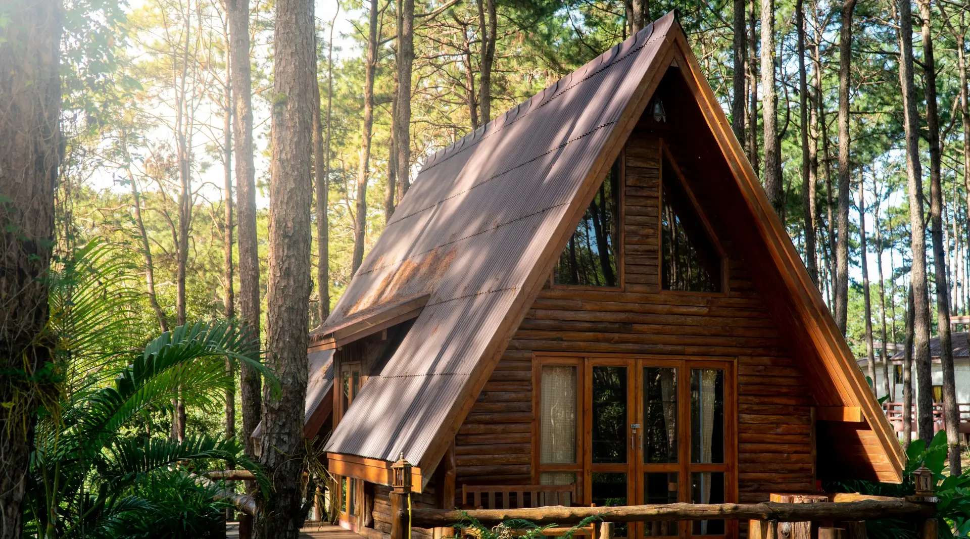 Wooden Hut in Forest Little wooden cottage house in forest. Log cabin hut with garret and giant pinewood trees in the morning sunlight.