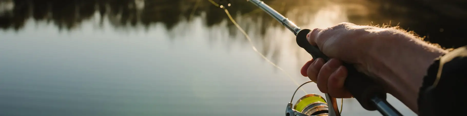 Fisherman with rod, spinning reel on the river bank. Sunrise. Fishing for pike, perch, carp. Fog against the backdrop of lake. background Misty morning. wild nature. The concept of a rural getaway.