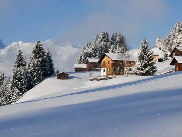 Verschneite Alpenlandschaft mit Bergen und weiter Naturkulisse als Motiv für Winterurlaub auf dem Land.