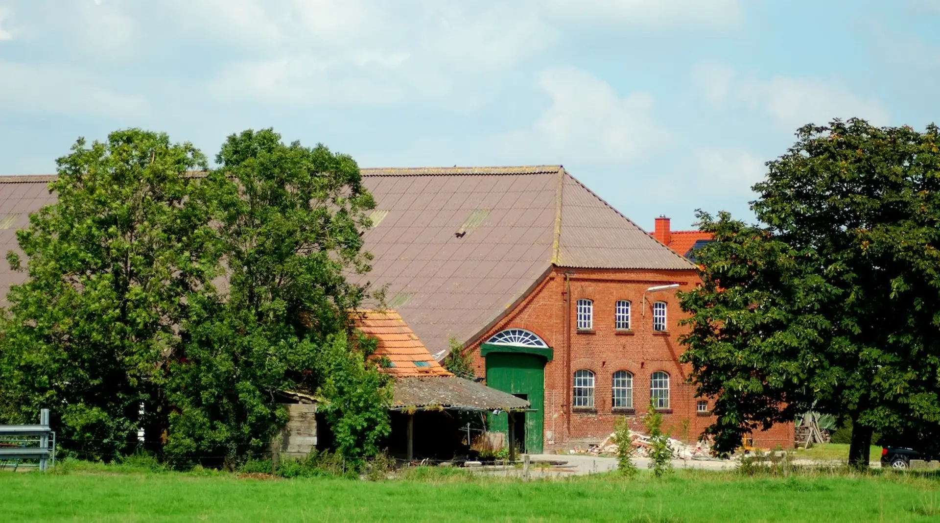 Alter friesischer Bauernhof in rotem Backstein mit grünem Scheunentor. 