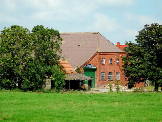Alter friesischer Bauernhof in rotem Backstein mit grünem Scheunentor. 