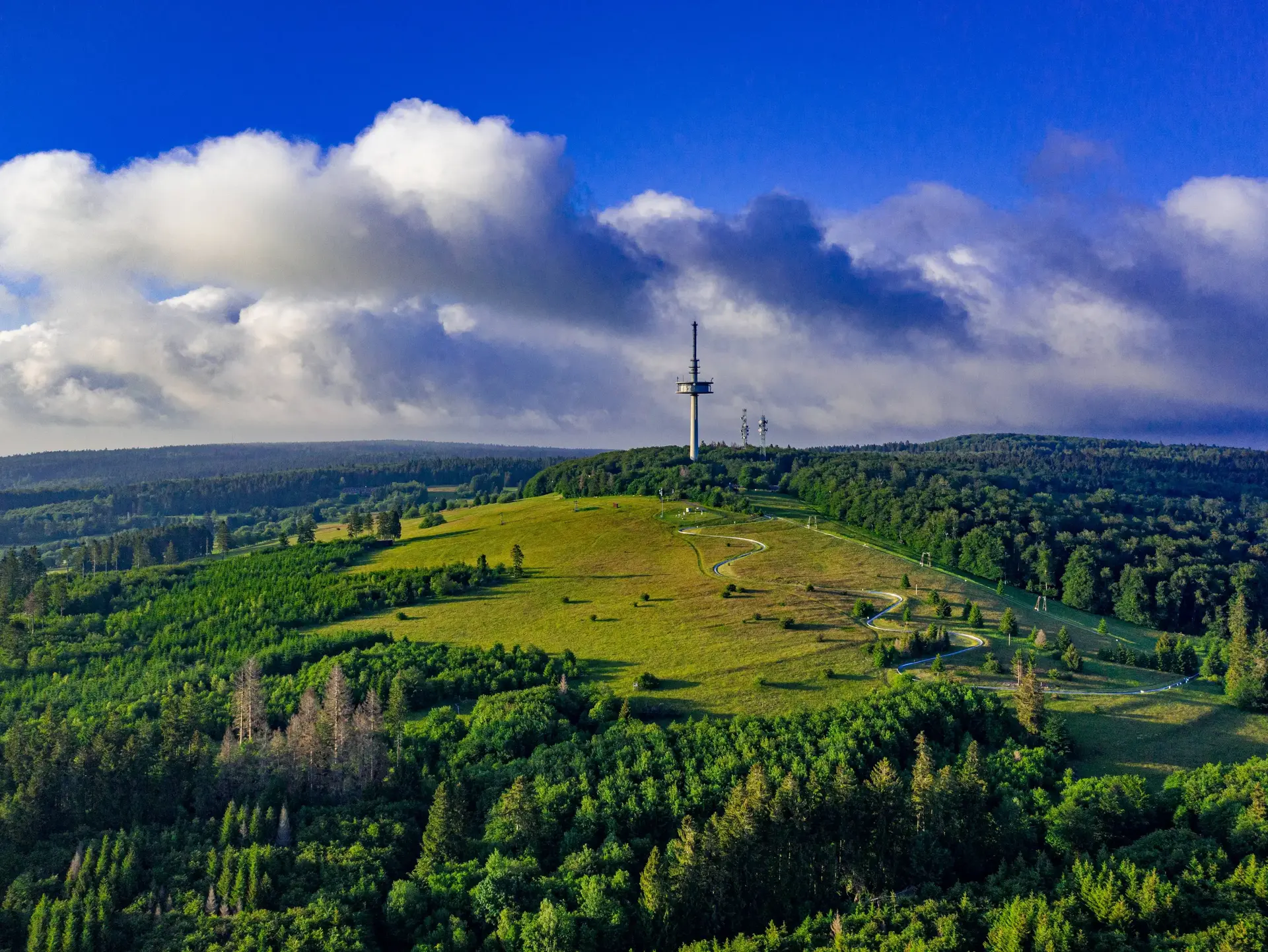 Luftaufnahme des Hoherodskopfs im Vogelsberg in Hessen mit bewaldeten Berghängen und Aussichtsturm.