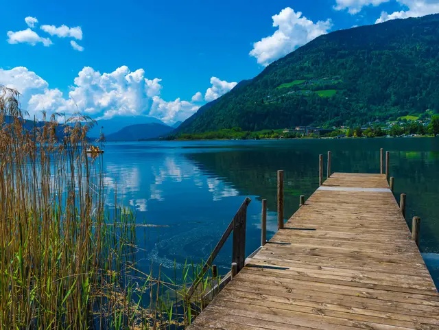 Ossiacher See – Holzsteg mit Blick auf Kärntens Bergwelt - © driendl, AdobeStock Holzsteg am Ufer des Ossiacher Sees mit Blick auf den See und die Berglandschaft in Kärnten.