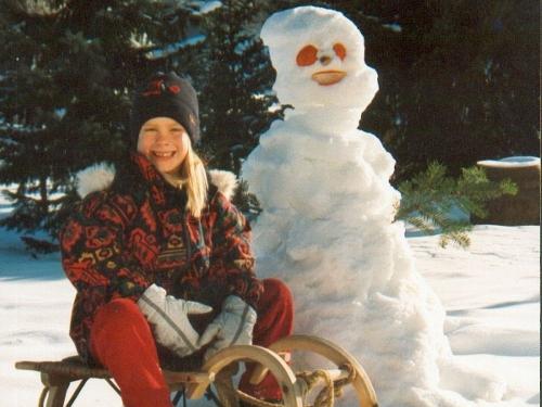 Kind mit Schneemann und Schlitten