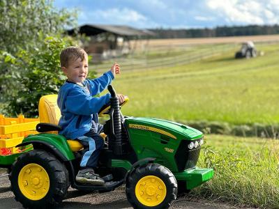 Junge auf dem Kindertraktor entdeckt den Hof