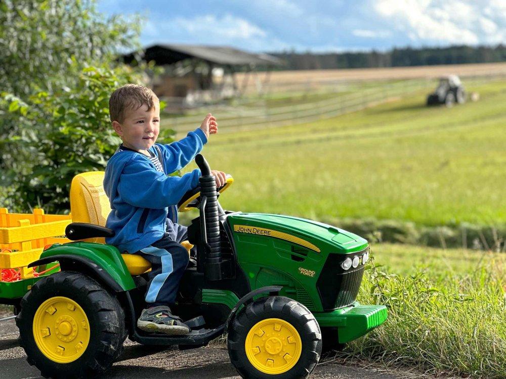 Junge auf dem Kindertraktor entdeckt den Hof